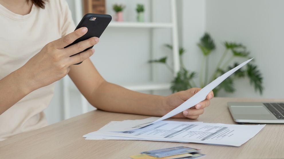 Symbolbild: Frau scannt Rechnung mit PDF-Scanner-App ihres Smartphones.