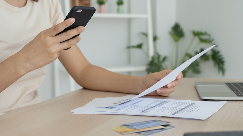 Symbolbild: Frau scannt Rechnung mit PDF-Scanner-App ihres Smartphones.