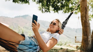 Symbolbild: Frau genießt mit Smartphone in der Hängematte ihren Urlaub.