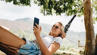 Symbolbild: Frau genießt mit Smartphone in der Hängematte ihren Urlaub.