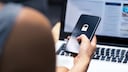 Person hält Smartphone mit einem Schloss-Symbol auf dem Display in der Hand