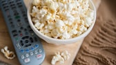 Eine Schüssel Popcorn neben einer TV-Fernbedienung