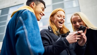 Junge Menschen gucken gemeinsam auf ein Smartphone und freuen sich tierisch