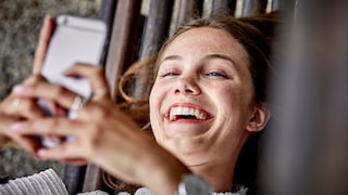 Frau schaut lachend auf ihr Smartphone