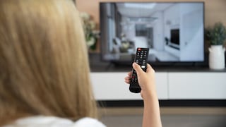 Frau mit Fernbedienung in der Hand vor einem 4K-Fernseher