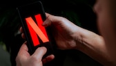 Person hält Smartphone mit Netflix in Händen