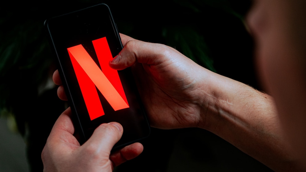 Person hält Smartphone mit Netflix in Händen