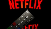 Netflix-Logo auf einem Fernseher, davor eine Fernbedienung