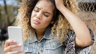 Frau schaut etwas verärgert auf ihr vielleicht OnePlus-Smartphone