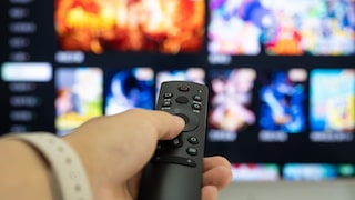 Person zeigt mit Fernbedienung auf ein Smart TV