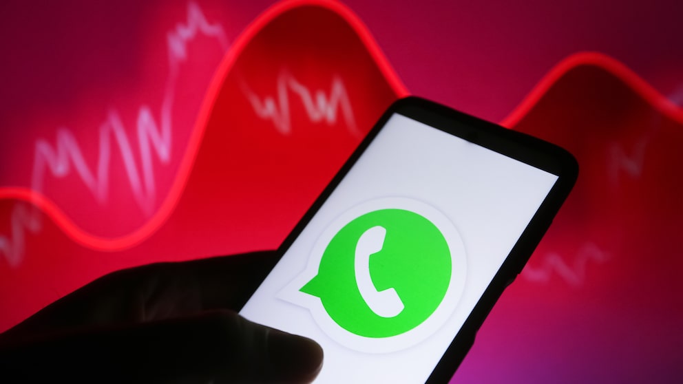 WhatsApp Logo auf einem Smartphone mit einem roten Hintergrund