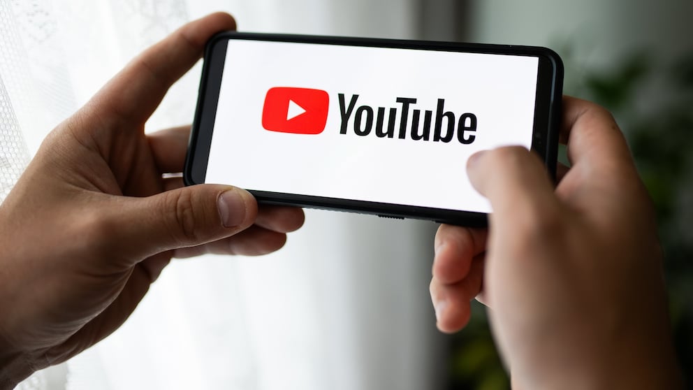 Person hält Smartphone mit YouTube in den Händen