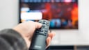 Fernseher im Hintergrund mit Fernbedienung