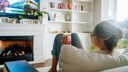 Frau sitzt mit Popcorn auf dem Sofa und sieht fern