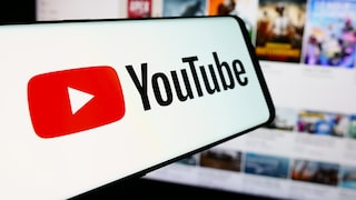 YouTube-Logo auf einem Smartphone mit Video-Thumbnails im Hintergrund