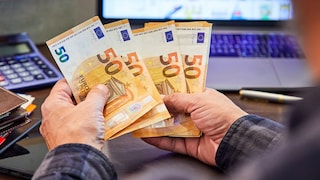 Mann hält mehrere 50-Euro-Banknoten in Händen
