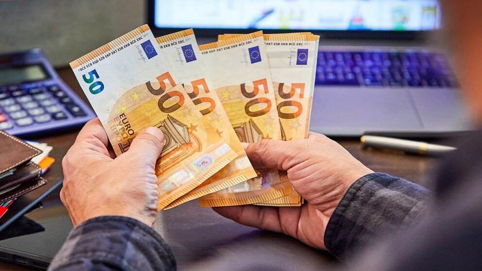 Mann hält mehrere 50-Euro-Banknoten in Händen