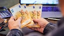 Mann hält mehrere 50-Euro-Banknoten in Händen