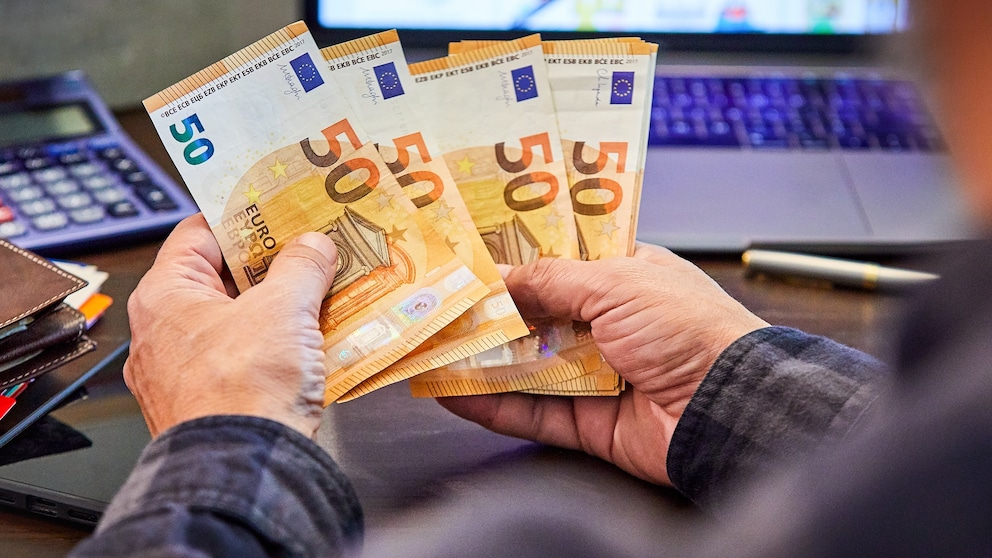 Mann hält mehrere 50-Euro-Banknoten in Händen