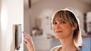 Frau bedient Smart-Home-Tablet an der Wand