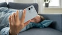 Person liegt auf dem Sofa und schaut aufs Smartphone