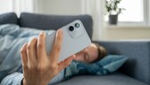 Person liegt auf dem Sofa und schaut aufs Smartphone