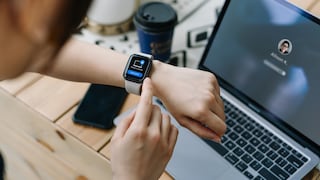 Smartwatch am Arm mit Laptop im Hintergrund