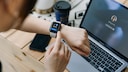Smartwatch am Arm mit Laptop im Hintergrund