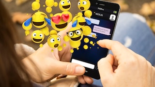 Person schaut auf ein Smartphone, über dem lauter Emojis schweben