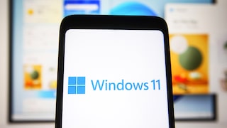 Windows 11 Logo auf einem Smartphone mit PC im Hintergrund