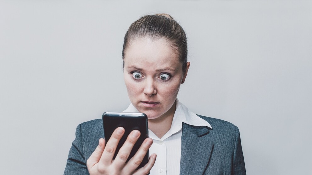 Frau schaut mit aufgerissenen Augen auf ihr Smartphone