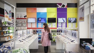 Frau in einem Elektrofachmarkt mit vielen Technik-Produkten und Smartphones