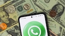 WhatsApp auf einem Smartphone auf einem Haufen US-Geld