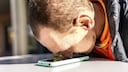 Mann hält seine Nase auf sein Smartphone