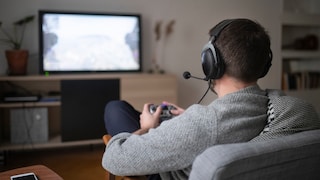 Mann sitzt vor dem Fernseher und spielt Videospiele