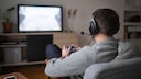 Mann sitzt vor dem Fernseher und spielt Videospiele