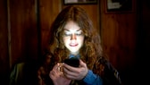 Frau schaut im Dunkeln auf ihr Smartphone