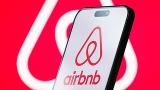 Airbnb-Logo auf einem Smartphone und im Hintergrund