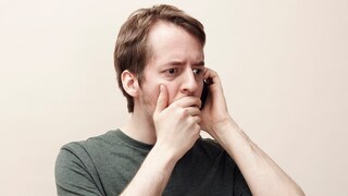 Mann telefoniert mit schockiertem Gesichtsausdruck