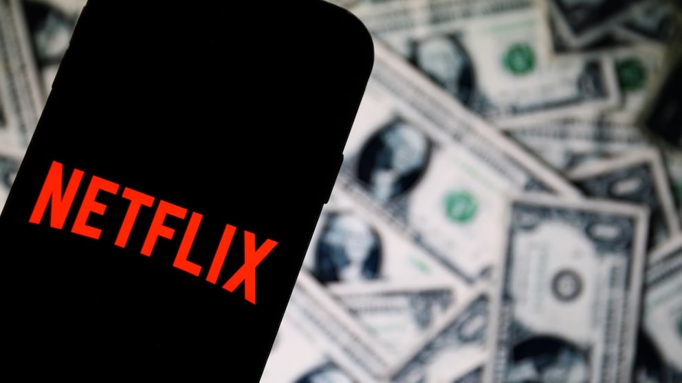 Netflix-Logo auf einem Smartphone, im Hintergrund US-Geld