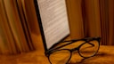 E-Book-Reader steht zwischen B&uuml;chern auf einem Tisch