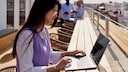 Frau arbeitet unter sonnigem, freien Himmel an ihrem Laptop