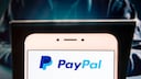 PayPal-Logo auf einem Display, im Hintergrund dubiose Person