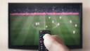 Person hält Fernbedienung auf einen Fernseher gerichtet