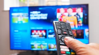 Hand hält Fernbedienung, Fernseher im Hintergrund