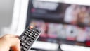 Person hält Fernbedienung auf einen TV gerichtet
