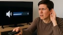 Person sitzt vor dem Fernseher und hört nicht richtig