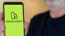 Mann hält Smartphone in der Hand, das Kleinanzeigen-Logeo ist zu sehen