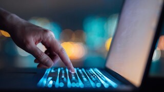 Person tippt auf einem Laptop