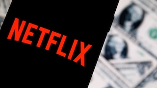 Netflix-Logo auf einem Smartphone, dahinter US-Dollar-Banknoten